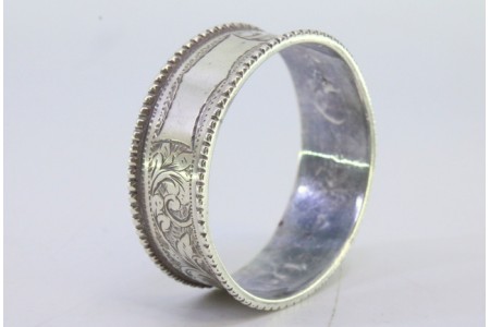 Argola de guardanapo com motivos florais gravados e duplo friso perlado.